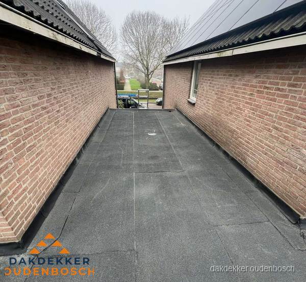 Plat dak met bitumen dakbedekking tussen bakstenen muren in Oudenbosch Plat dak met bitumen dakbedekking tussen bakstenen muren in Oudenbosch