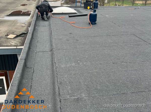 Dakdekker repareert bitumen dakbedekking op groot plat dak in Oudenbosch Dakdekker repareert bitumen dakbedekking op groot plat dak in Oudenbosch