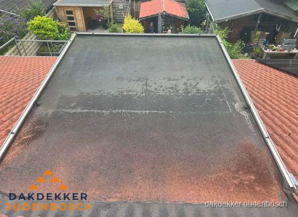 Verouderd plat dak met slijtage tussen schuine daken in Oudenbosch Verouderd plat dak met slijtage tussen schuine daken in Oudenbosch