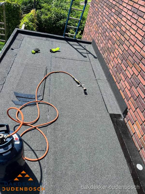 Plat dak met bitumen en brandgereedschap van dakdekkersbedrijf in Oudenbosch